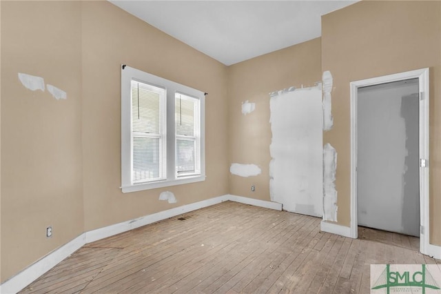 empty room with hardwood / wood-style floors and baseboards