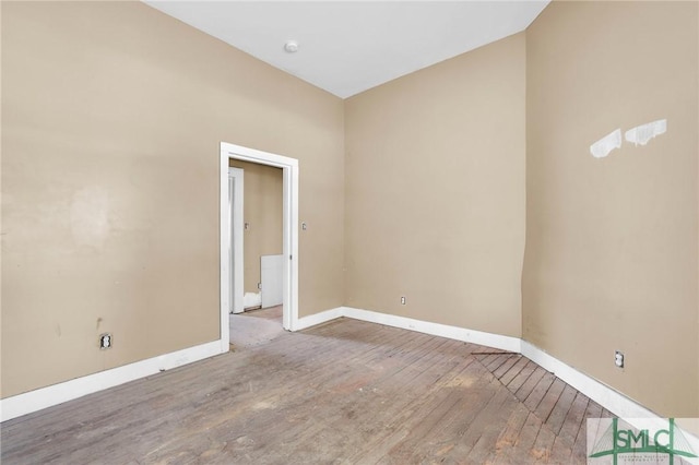 empty room featuring hardwood / wood-style flooring and baseboards