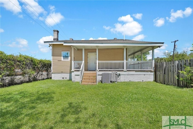 rear view of house featuring a porch, fence, and a lawn