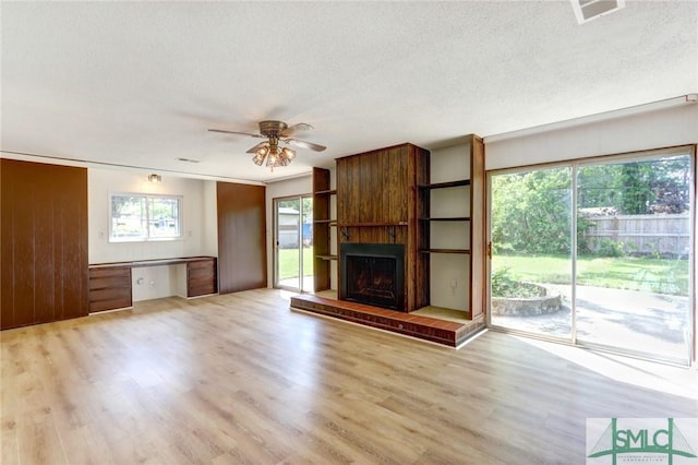 12445 Deerfield Rd, Savannah, GA 31419 - unfurnished living room featuring visible vents, ceiling fan, a textured ceiling, a large fireplace, and light wood-style flooring