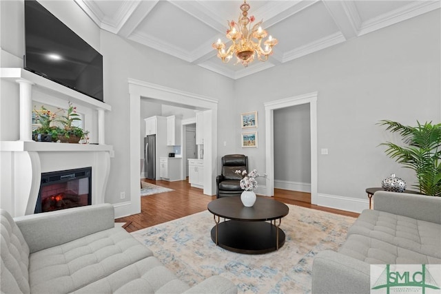 living room featuring baseboards, an inviting chandelier, wood finished floors, coffered ceiling, and a glass covered fireplace