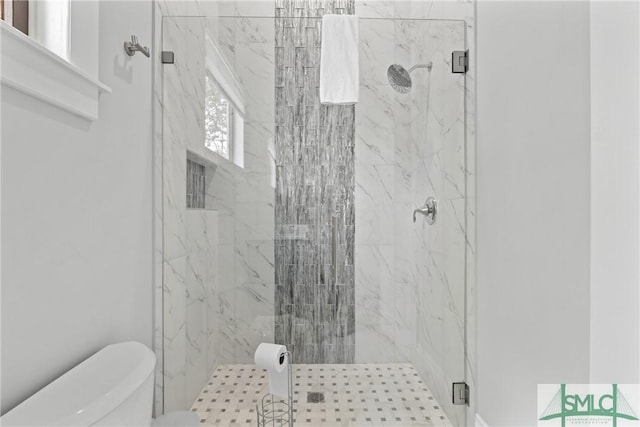 bathroom featuring a marble finish shower and toilet