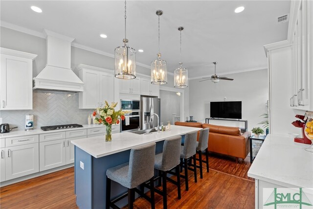 kitchen with custom exhaust hood, visible vents, a sink, ornamental molding, and appliances with stainless steel finishes