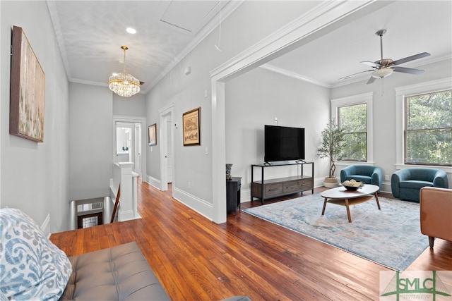 living area with crown molding, ceiling fan with notable chandelier, baseboards, and hardwood / wood-style flooring