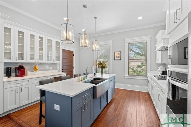 kitchen featuring stainless steel oven, white cabinetry, a sink, light countertops, and a breakfast bar area