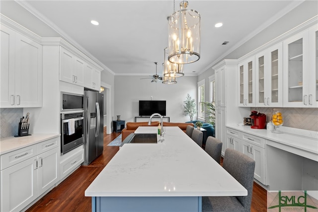 kitchen featuring crown molding, white cabinets, a sink, stainless steel appliances, and open floor plan