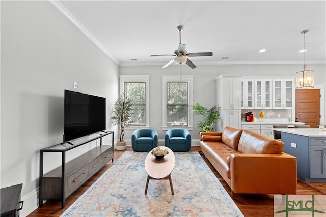 living area featuring dark wood-style flooring, ornamental molding, a ceiling fan, and visible vents