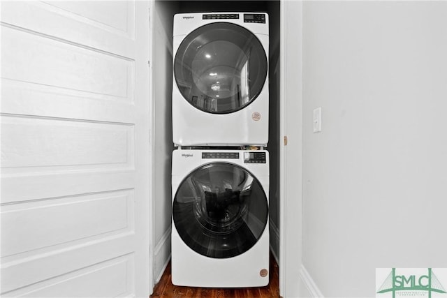 laundry area featuring stacked washing maching and dryer, laundry area, and wood finished floors