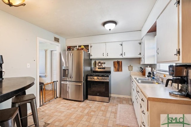 kitchen with light countertops, white cabinetry, visible vents, stainless steel appliances, and a sink