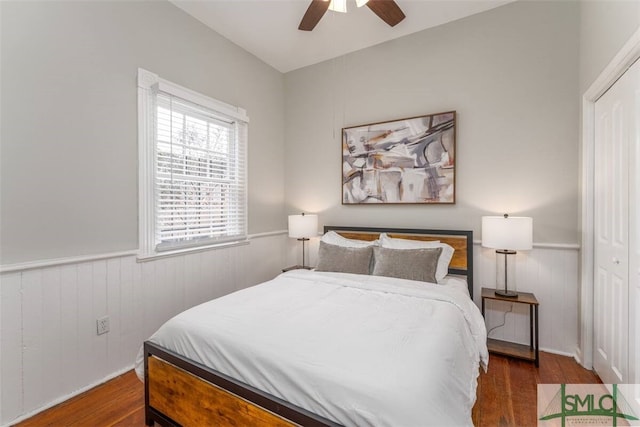bedroom featuring ceiling fan, wainscoting, and wood finished floors