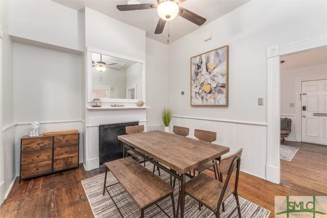 dining space featuring hardwood / wood-style floors, a ceiling fan, wainscoting, and a fireplace