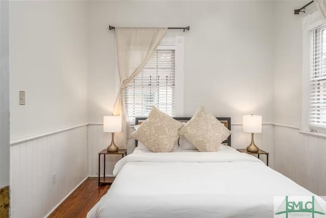 bedroom with wainscoting and wood finished floors