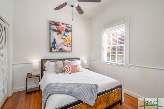 bedroom with a closet, a wainscoted wall, and wood finished floors