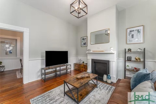 living area featuring a fireplace with flush hearth, wood finished floors, and a chandelier