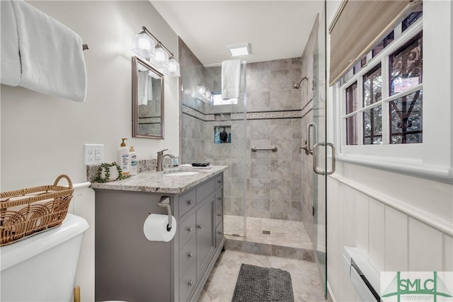 full bathroom with vanity, toilet, a stall shower, and baseboard heating