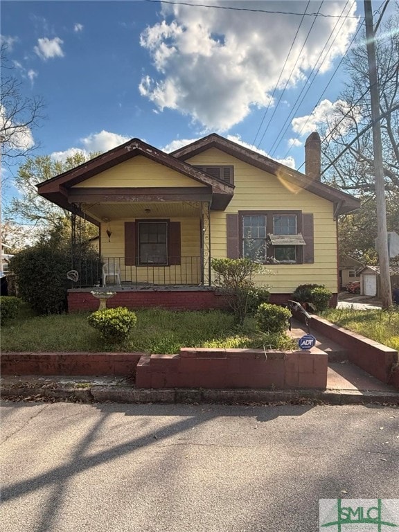 bungalow featuring a chimney and covered porch