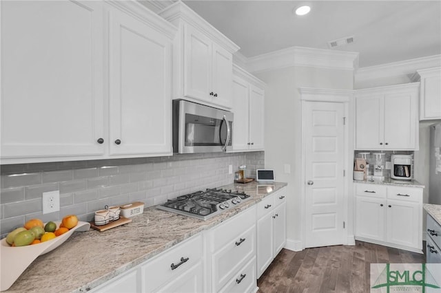 kitchen featuring white cabinets, visible vents, light stone counters, dark wood-type flooring, and appliances with stainless steel finishes