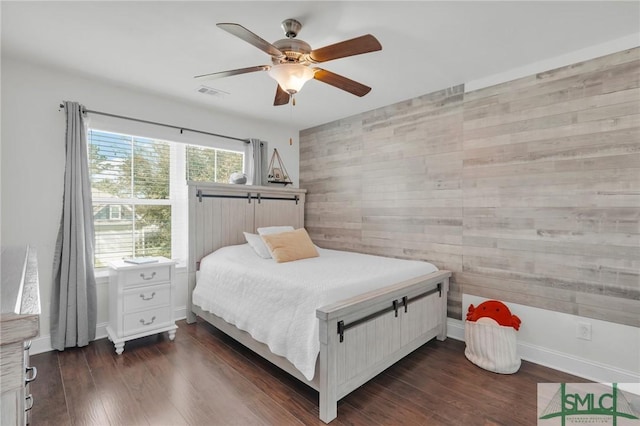 bedroom with visible vents, dark wood-style flooring, an accent wall, and ceiling fan