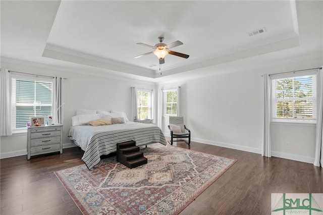 bedroom with visible vents, a tray ceiling, crown molding, and dark wood-style floors