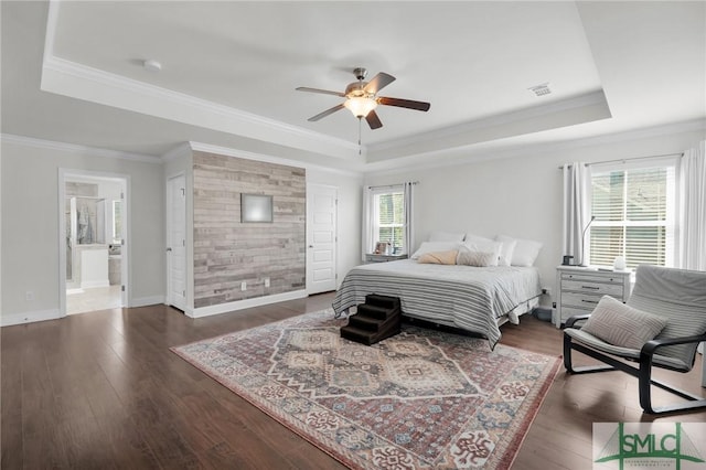 bedroom with crown molding, visible vents, wood finished floors, a raised ceiling, and baseboards