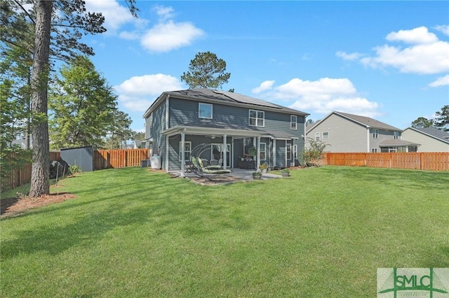 back of property featuring roof mounted solar panels, a fenced backyard, a patio area, and a lawn