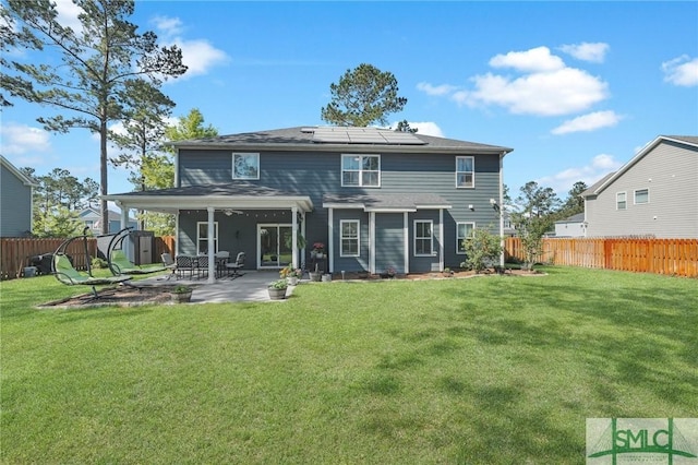 back of property featuring a patio area, solar panels, a fenced backyard, a lawn, and a storage unit