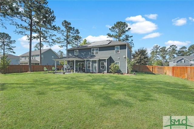 back of house featuring a patio, solar panels, a fenced backyard, and a lawn