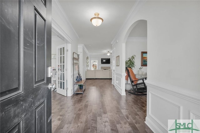 foyer entrance featuring arched walkways, wood finished floors, ceiling fan, and crown molding