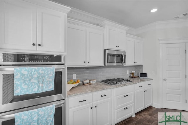 kitchen featuring backsplash, white cabinets, dark wood-type flooring, visible vents, and appliances with stainless steel finishes