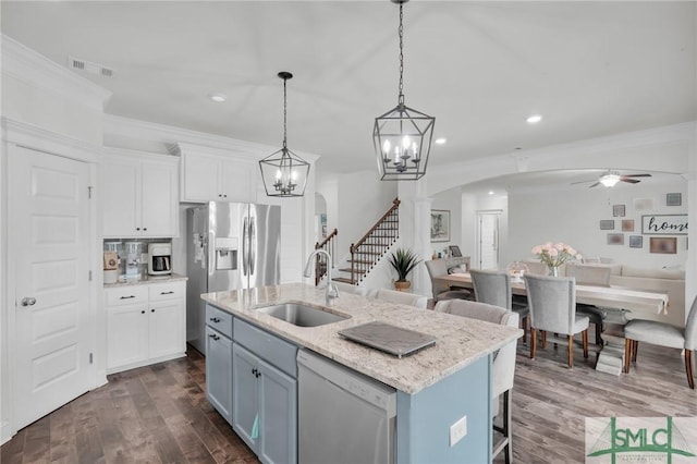 kitchen with ceiling fan with notable chandelier, dishwashing machine, arched walkways, a sink, and open floor plan
