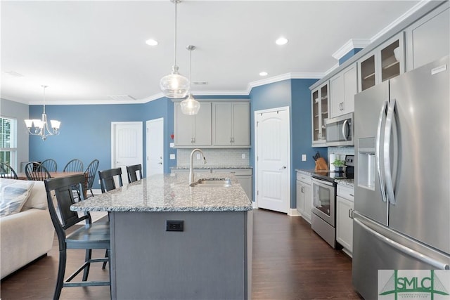 kitchen with a sink, ornamental molding, stainless steel appliances, decorative backsplash, and a breakfast bar area