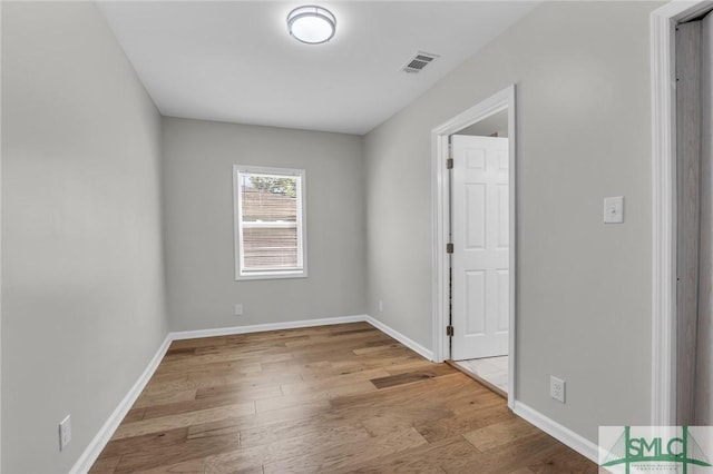spare room with baseboards, wood finished floors, and visible vents