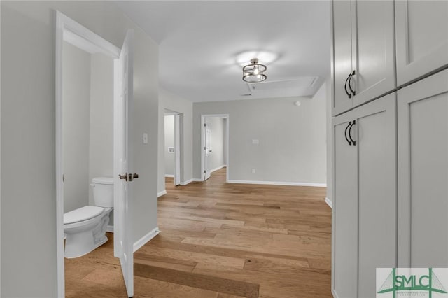 corridor with light wood-type flooring and baseboards