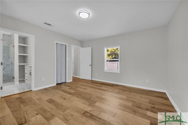 unfurnished bedroom featuring baseboards, connected bathroom, light wood-style flooring, and visible vents