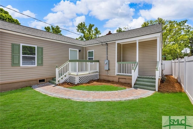 rear view of house featuring fence and a yard