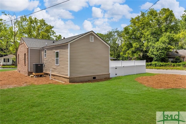 view of side of home featuring a lawn, central AC, fence, and crawl space