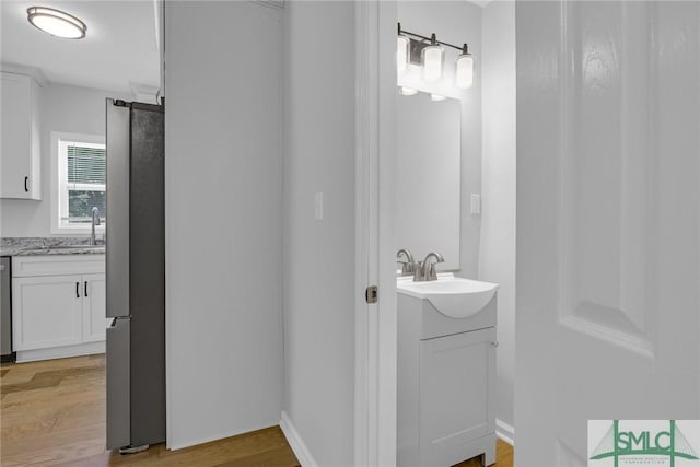 bathroom featuring two vanities, a sink, and wood finished floors