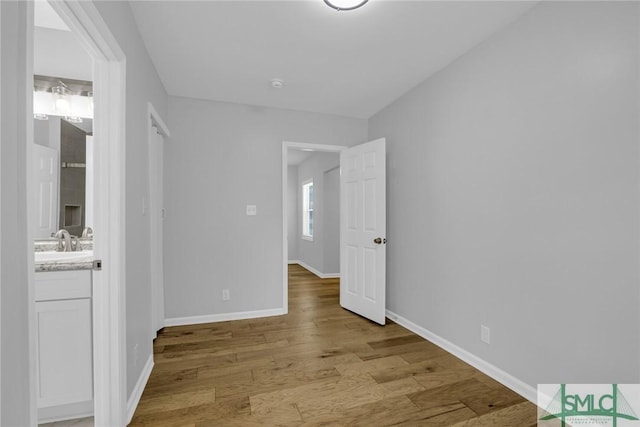unfurnished bedroom featuring light wood-style floors, a sink, and baseboards