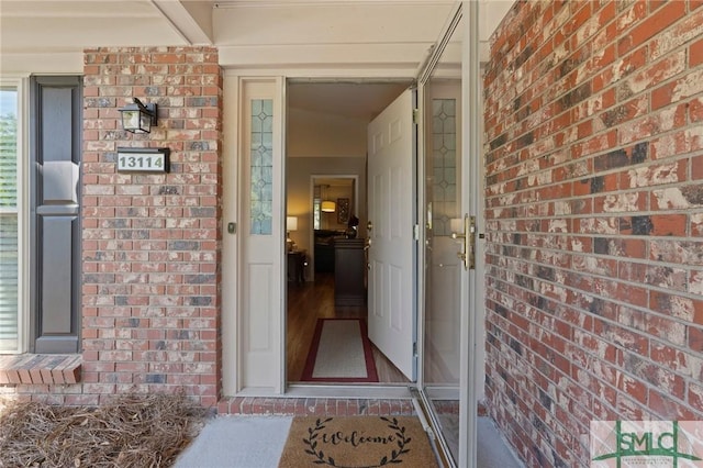 entrance to property featuring a porch and brick siding