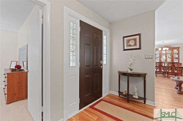 foyer entrance featuring a chandelier, light wood-type flooring, and baseboards