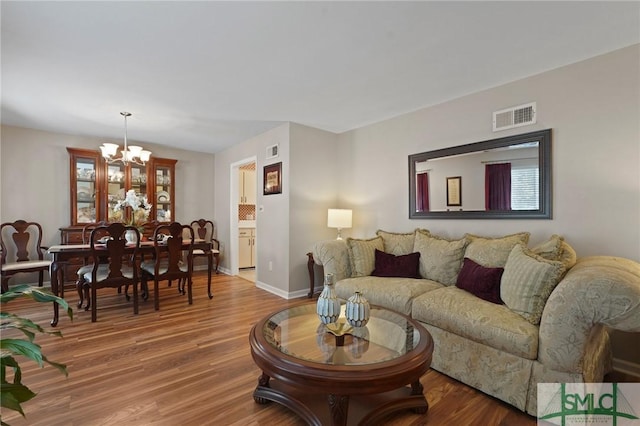 living room featuring wood finished floors, an inviting chandelier, and visible vents