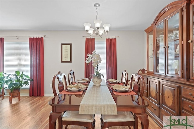 dining room with a chandelier, light wood-style flooring, and baseboards