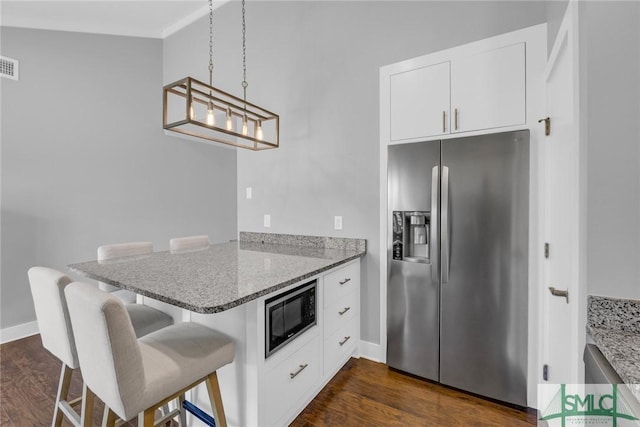 kitchen featuring a kitchen breakfast bar, built in microwave, stainless steel fridge with ice dispenser, a peninsula, and dark wood-style flooring