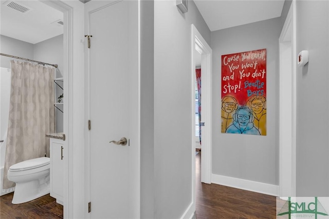hallway with baseboards, visible vents, and dark wood-style floors