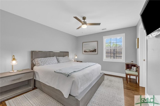 bedroom featuring wood finished floors, visible vents, baseboards, and ceiling fan