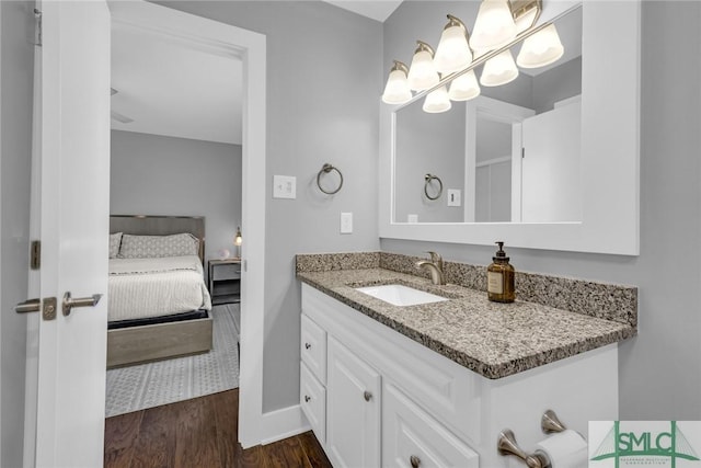 ensuite bathroom with baseboards, ensuite bathroom, wood finished floors, and vanity