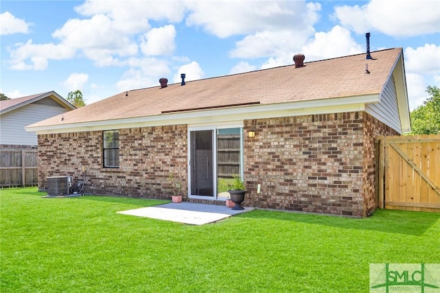 rear view of property featuring cooling unit, fence, brick siding, a lawn, and a patio