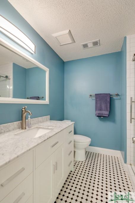 bathroom featuring a textured ceiling, a stall shower, vanity, toilet, and visible vents