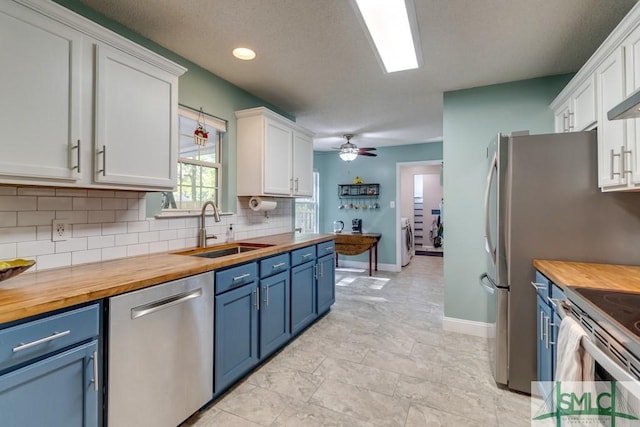 kitchen with wood counters, appliances with stainless steel finishes, blue cabinets, and a sink