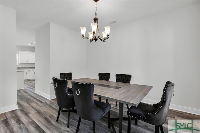 dining space featuring wood finished floors, visible vents, baseboards, and a notable chandelier
